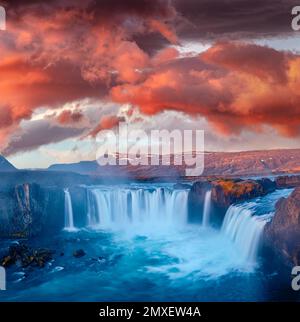 Wunderschöne nordische Landschaft. Mystischer Blick am Morgen auf den Godafoss Wasserfall mit roten Wolken darüber. Atemberaubender Sonnenaufgang im Sommer in Island, Europa. Schönheit von Stockfoto