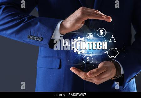 FinTech-Konzept. Ein Mann, der verschiedene Symbole auf dunklem Hintergrund zeigt, Nahaufnahme Stockfoto