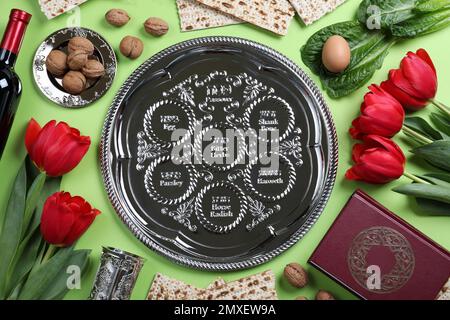 Flache Laienzusammensetzung mit symbolischen Pesach-Elementen (Passover Seder) auf hellgrünem Hintergrund Stockfoto