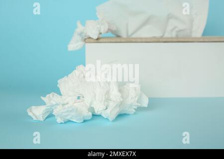 Gebrauchte Papiertücher und Halter auf hellblauem Hintergrund, Nahaufnahme Stockfoto