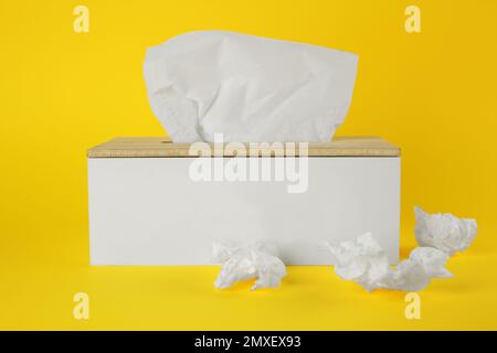 Gebrauchte Papiertücher und Halter auf gelbem Hintergrund Stockfoto