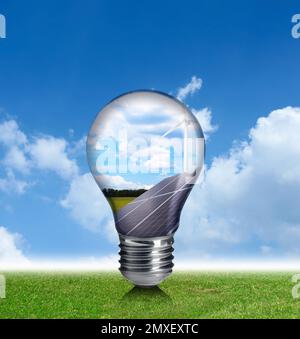 Alternative Energiequelle. Glühlampe mit Solarpaneelen und Windturbinen im Freien Stockfoto