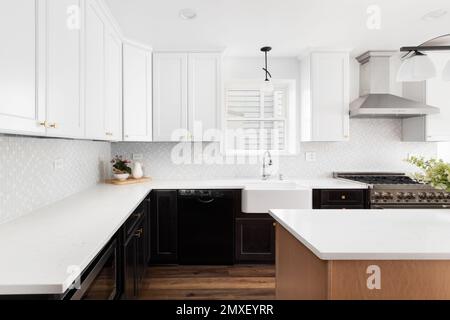 Eine gemütliche Bauernhausküche mit Holz- und weißen Schränken, gefliesten Backplash-Elementen und Marmorarbeitsflächen. Stockfoto