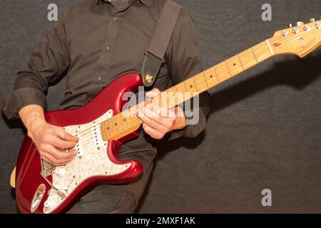 Vaduz, Liechtenstein, 23. Dezember 2022 Musiker spielt mit einer Fender Stratocaster USA Elektrogitarre in Rot Stockfoto