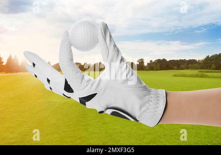 Ein Spieler, der am sonnigen Tag einen Golfball im Park hält, schließt Stockfoto