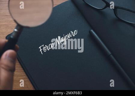 Eine Hand mit einer Lupe, einer Brille, einem Stift und einem Notizbuch, die mit höherer Gewalt geschrieben wurden. Stockfoto