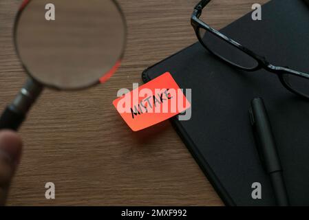 Eine Hand, die eine Lupe hält und auf ein Buch zeigt, dessen Etikett versehentlich geschrieben wurde. Stockfoto