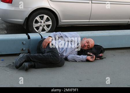 Ein Obdachloser, der auf dem Bürgersteig liegt. Stockfoto