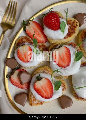 Ein vertikaler Schuss mit Donuts, serviert mit Erdbeeren, Sahne und herzförmiger Schokolade Stockfoto