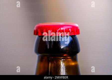 Flaschenhals aus braunem Glas mit rotem Metallverschluss. Nahaufnahme der ungeöffneten Flasche. Stockfoto