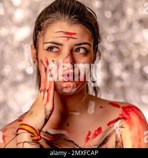 Ein verspieltes Porträt einer jungen, aufmerksamen Frau, bedeckt mit Farbe Stockfoto