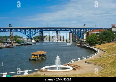 Ein strohgedecktes Gruppenboot, das von CLE Tiki Barge Motoren am Brunnen im Settlers Landing Park in Cleveland, Ohio, vorbeifährt. Stockfoto