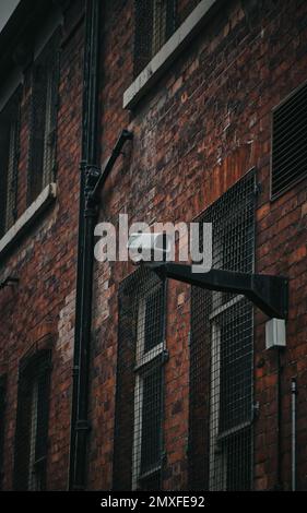 Eine Überwachungskamera an einer Metallbar an der Seite eines Gebäudes mit braunen Ziegeln in Nottingham Stockfoto
