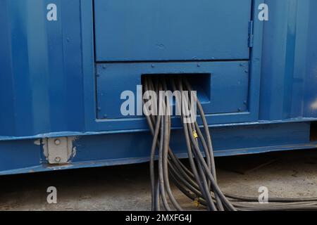 Nahaufnahme des Bündels schwarzer Kabel kommt aus dem blauen Netzteil oder tragbaren Generator für die Stromversorgung der Kühlschränke. Stockfoto