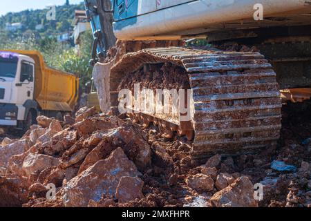 Schwere Maschinenarbeiten auf der Baustelle. Rodung von steinigem Boden für den Bau in der Türkei. Der Raupenbagger steht auf Felsen. Stockfoto