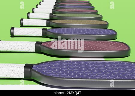 Pickleball, verschiedene Schläger, die in einer Reihe auf einem Sportspielplatz liegen. Nahaufnahme des 3D-Renderings Stockfoto