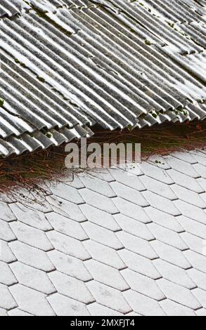 Der Rand von zwei Dächern mit verschiedenen Beschichtungen, die mit frischem Schnee bedeckt sind. Selektiver Fokus Stockfoto