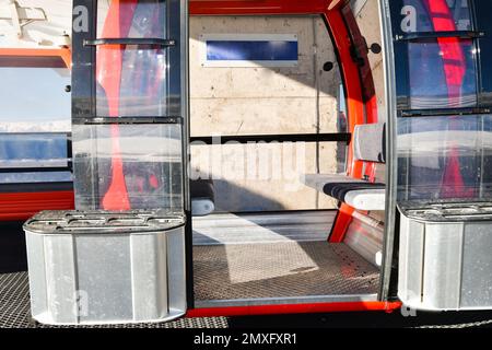 Roter Seilbahnlift mit offener Tür und leeren Sitzen im Skigebiet Goderdzi. Georgien Stockfoto