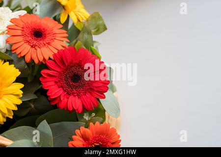 Gerber Daisy sitzt einen schönen Korb auf dem lokalen Bauernmarkt. Bouquet mit sanften gelben, roten, orangefarbenen Gänseblümchen und rosa Blumen. Feier Stockfoto