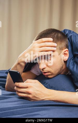 Verärgert verwirrter junger Mann, der ein Handy in der Hand hat, Probleme mit dem Handy hat oder einen verpassten Anruf hat, frustrierter wütender Schüler, der schlechte Nachrichten in der Nachricht liest, schau Stockfoto