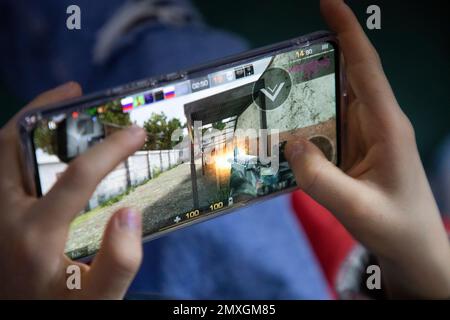 Ein Kind spielt das mobile Multiplayer-Online-Spiel Standoff 2 auf einem Telefon Stockfoto