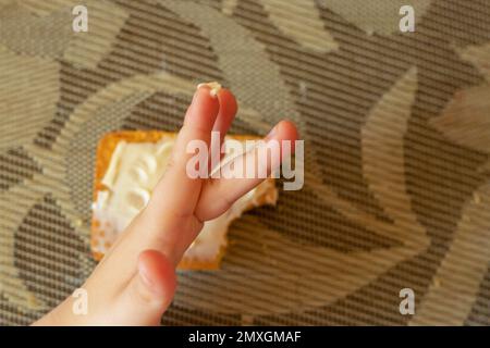 Kinderhände und Kekse mit Butter auf dem Tisch Stockfoto