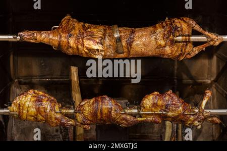 Lamm auf gegrillten Spießen mit heißer Holzkohle. Das Lamm wird komplett auf einem Spieß auf dem Feuer gekocht. Kochen. Stockfoto