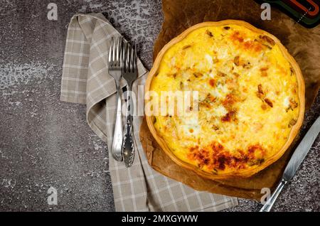 Quiche – Offene Tortenkuchen mit Hühnerfleisch, Champignons, Pilzen, Zwiebeln und Käse auf einem weißen Tisch. Hausgemachter Kuchen. Französische Küche Stockfoto