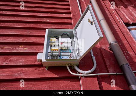 Eine externe Schalttafel mit elektrischem Zähler hängt an der Wand eines hölzernen Landhauses. Stockfoto