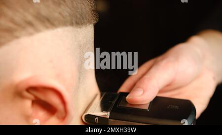 Nahaufnahme von Männerfrisur und Haarschnitt mit Frisiermaschine, Haarschnitt für Männchen. Friseurservice mit Rasierer in einem modernen Friseursalon in einem Stockfoto