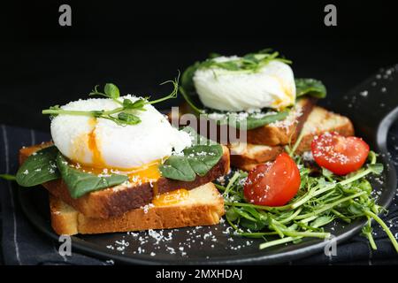 Köstliche pochierte Ei-Sandwiches, serviert auf Schieferbrett Stockfoto