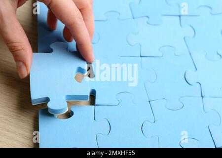 Frau, die ein hellblaues Puzzleteil legt, mit Platz für Text. Konzept der beruflichen Beförderung Stockfoto