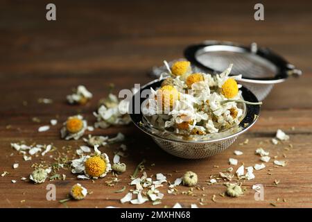 Trockene Kamillenblüten im Infusor auf Holztisch, Nahaufnahme Stockfoto