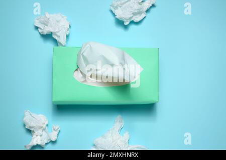 Gebrauchte Papiertücher und Schachtel auf hellblauem Hintergrund, flach liegend Stockfoto