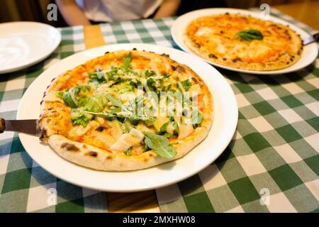 Frische hausgemachte, authentische italienische caesar-Pizza aus Steinofen mit Rucola, Sauce, gegrilltem Hähnchen, Kräutern und würzigem Parmesankäse und margherita. Stockfoto