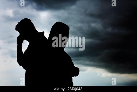 Silhouetten eines streitenden Paares gegen den Himmel mit schweren Regenwolken. Beziehungsprobleme Stockfoto