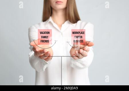 Konzept der Work-Life-Balance. Eine Frau, die eine Waage mit Wörtern auf hellem Hintergrund illustriert, Nahaufnahme Stockfoto