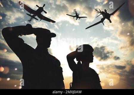 Silhouetten von Soldaten, die salutieren, und Flugzeuge in der Kampfzone. Militärdienst Stockfoto