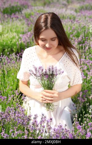 Junge Frau mit lavendelfarbenem Blumenstrauß auf dem Feld am Sommertag Stockfoto