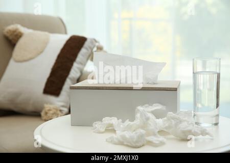 Gebrauchte Papiertücher, Halter und Wasser auf dem Tisch in Innenräumen Stockfoto