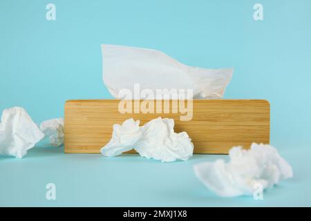 Gebrauchte Papiertücher und Holzhalter auf hellblauem Hintergrund Stockfoto