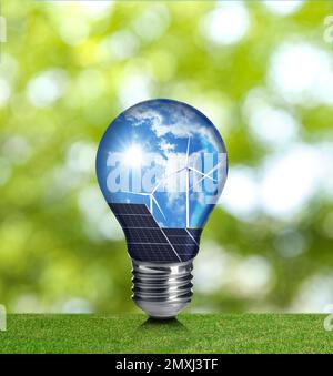Alternative Energiequelle. Glühlampe mit Solarpaneelen und Windturbinen im Freien Stockfoto