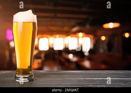 Frisches kaltes Bier auf Holztisch im Pub, Platz für Text Stockfoto