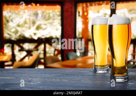 Frisches kaltes Bier auf Holztisch im Pub, Platz für Text Stockfoto