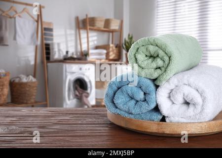 Tablett mit sauberen weichen Handtüchern auf Holztisch im Badezimmer. Platz für Text Stockfoto