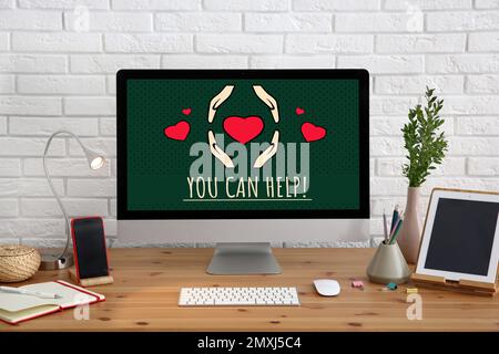 Das Spendenkonzept. Computer mit Text, DEN SIE auf einem Holztisch im Büro AUSHELFEN können Stockfoto