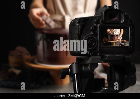 Lebensmittelfotografie. Schießen von Koch, der Schokoladenkuchen dekoriert, Fokus auf Kamera Stockfoto