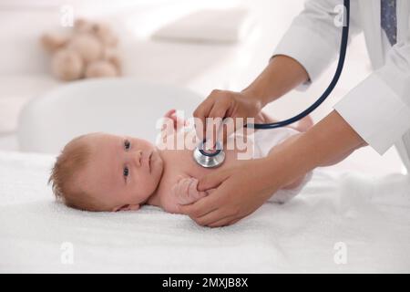 Doktor untersucht süßes Baby mit Stethoskop drinnen, Nahaufnahme. Gesundheitsfürsorge Stockfoto