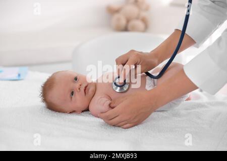 Doktor untersucht süßes Baby mit Stethoskop drinnen, Nahaufnahme. Gesundheitsfürsorge Stockfoto