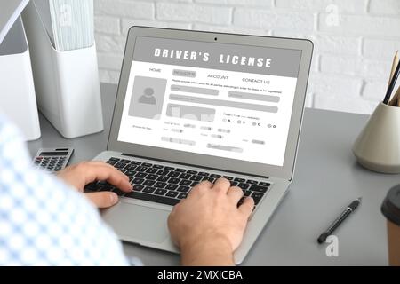 Mann, der den Führerschein online auf der Website ausfüllt, mit Laptop, Nahaufnahme Stockfoto